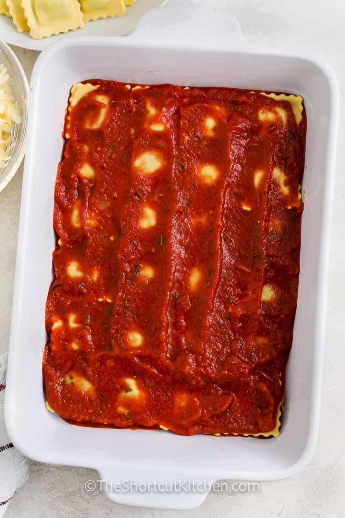 adding more sauce to ravioli to make Ravioli Lasagna Recipe
