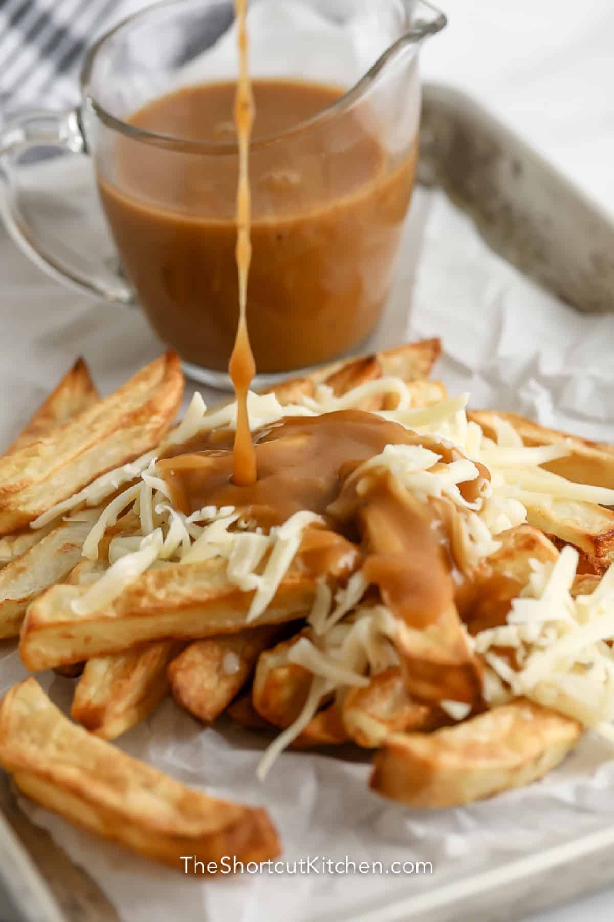 gravy poured over parchment lined tray of fries with cheese