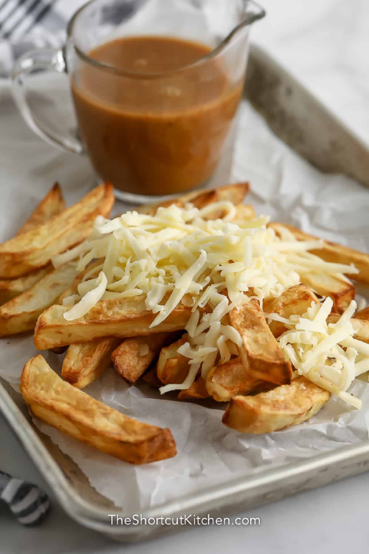 parchment lined tray of fries with cheese grated on top