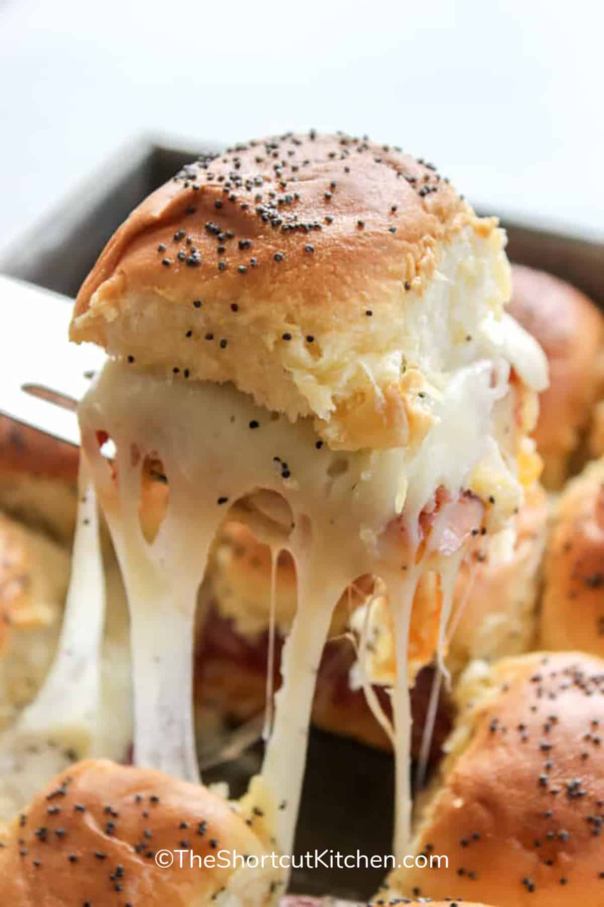 one cheesy Easy Italian Sliders being lifted out of a pan, showing the gooey melted cheese