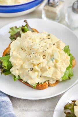 the best egg salad recipe with lettuce on a slice of bread, on a white plate