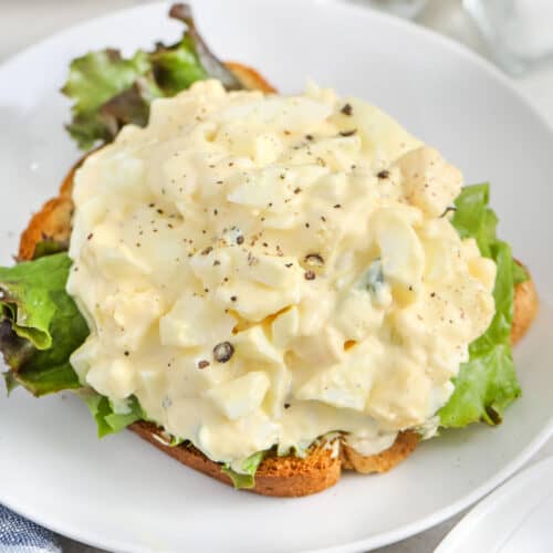 the best egg salad recipe with lettuce on a slice of bread, on a white plate