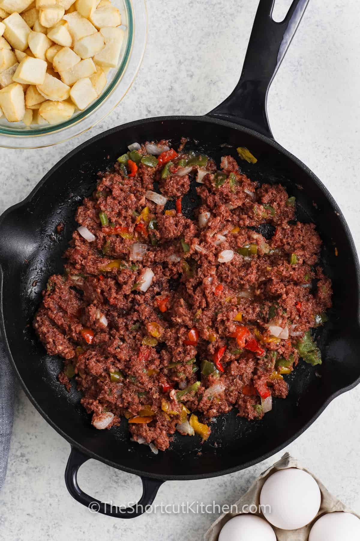 adding corned beef to vegetable mix to make Canned Corned Beef Hash