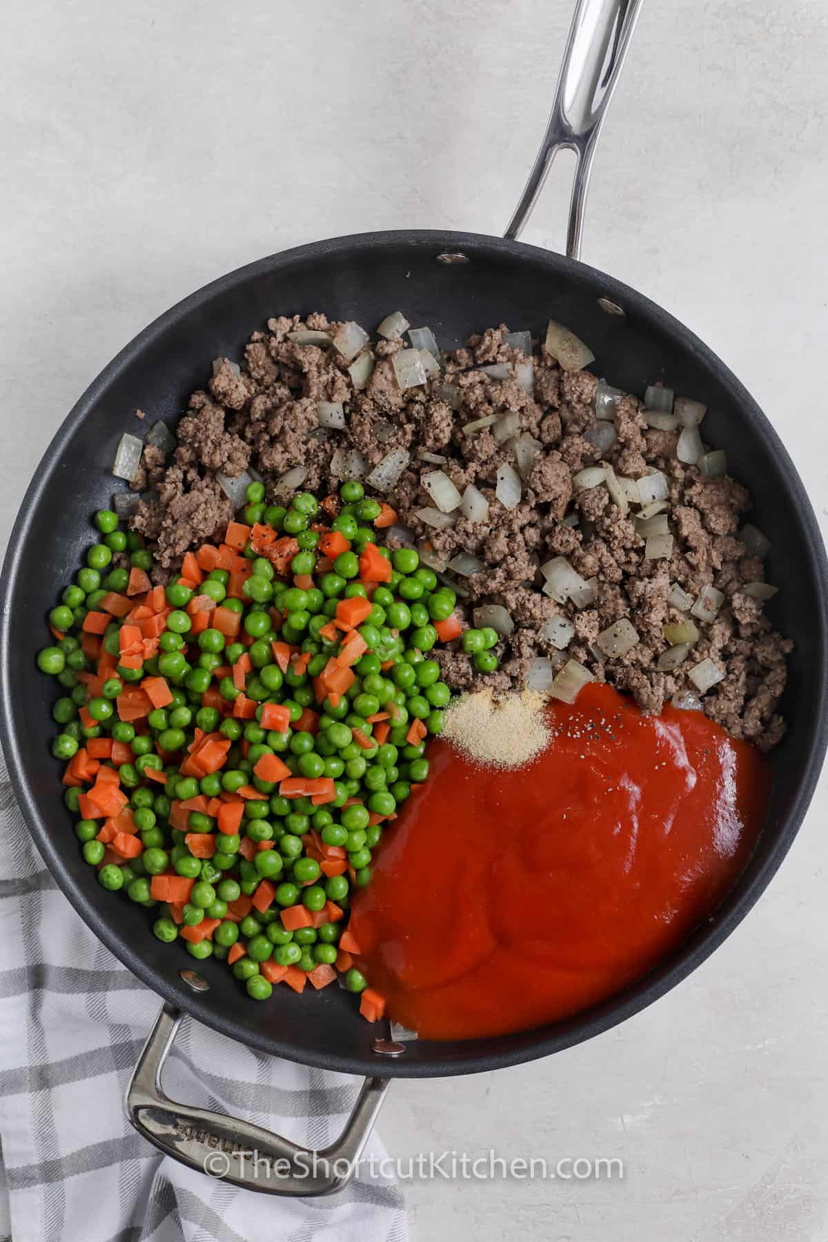 adding sauce and vegetables to ground beef in pan to make Cottage Pie Baked Potatoes