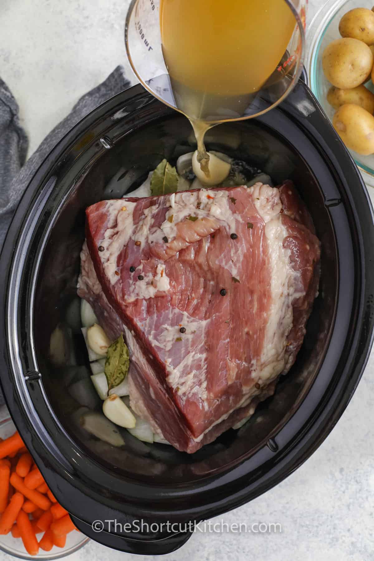 adding broth to crockpot to make Crock Pot Corned Beef and Cabbage