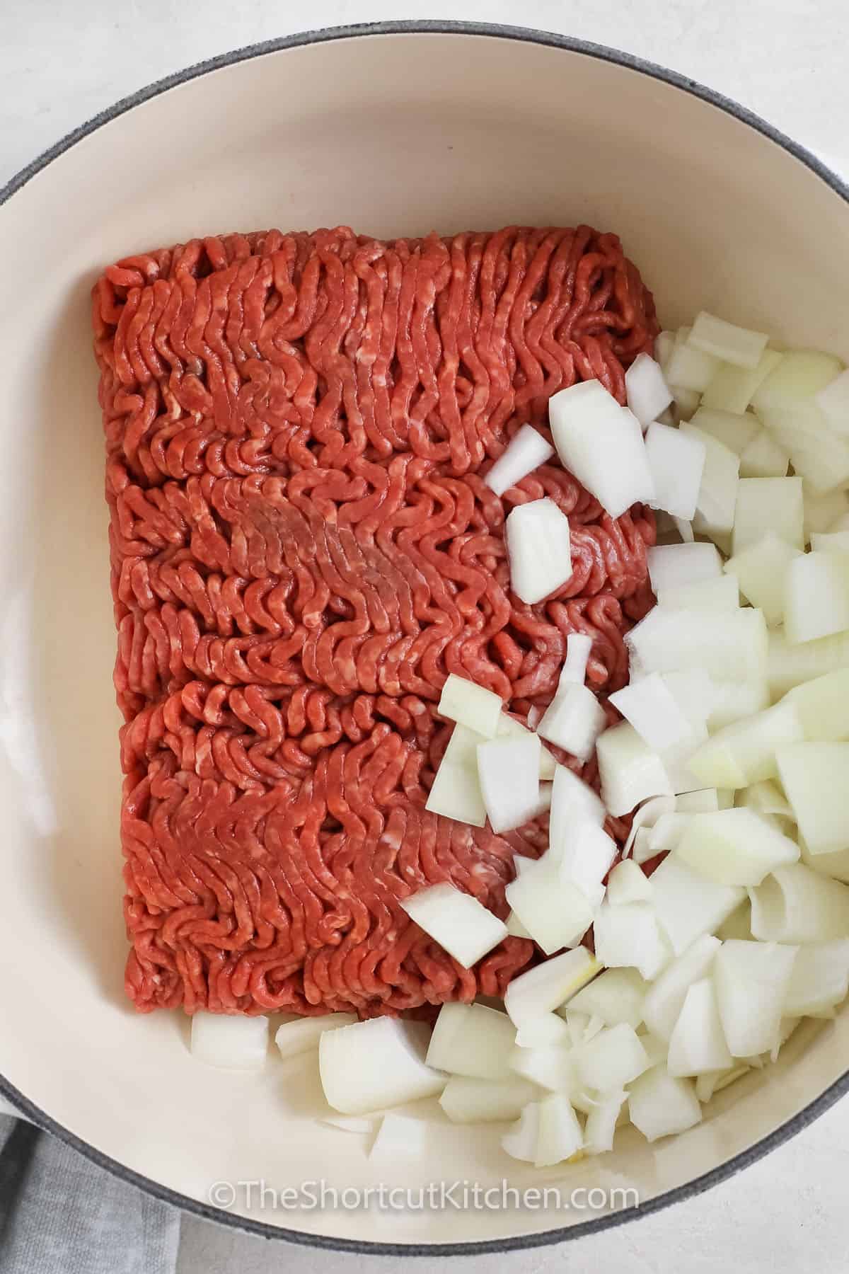 adding onions to ground beef in a pot to make ground beef soup