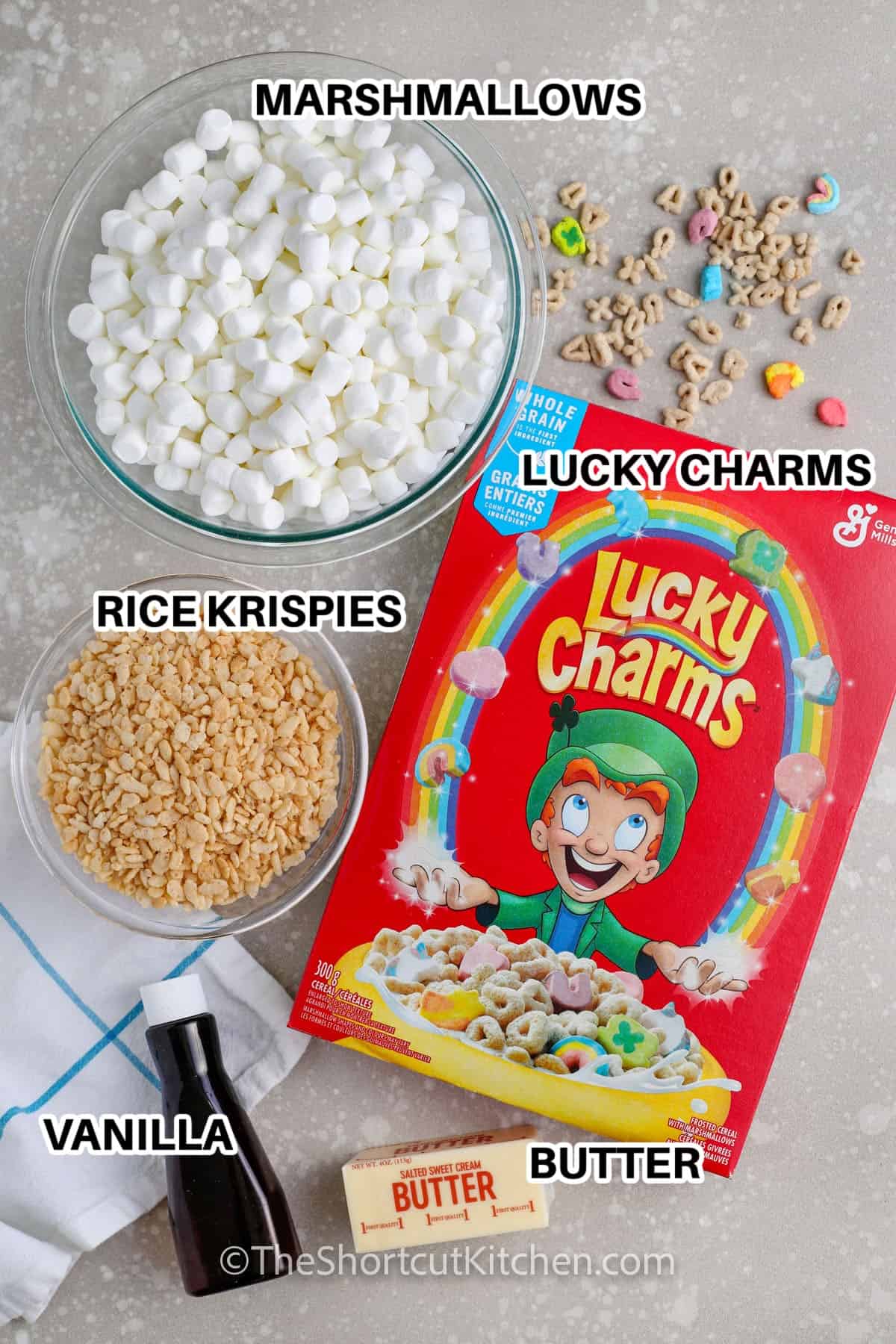 Ingredients to make Lucky Charms Rice Krispie Treats labeled: Marshmallows, lucky charms, rice krispies, vanilla, and butter
