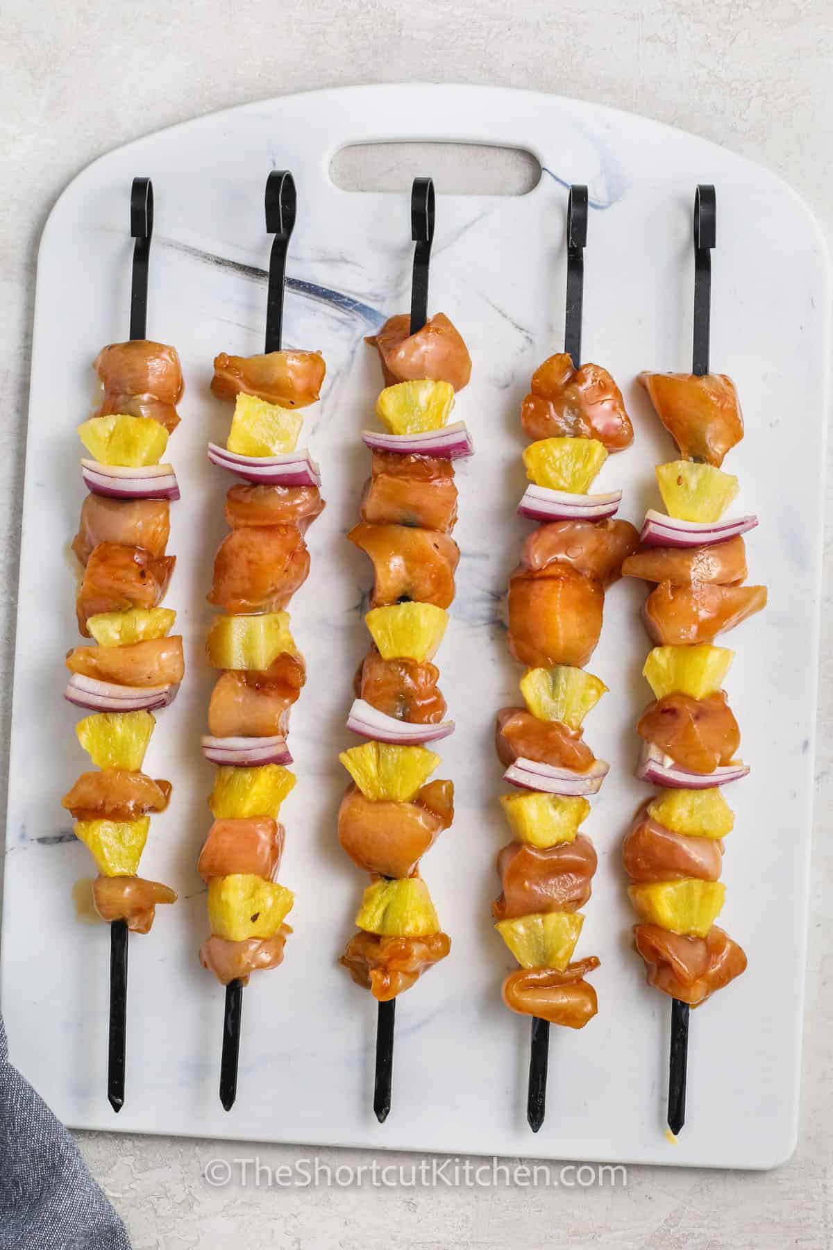 uncooked grilled pineapple chicken kabobs on a cutting board