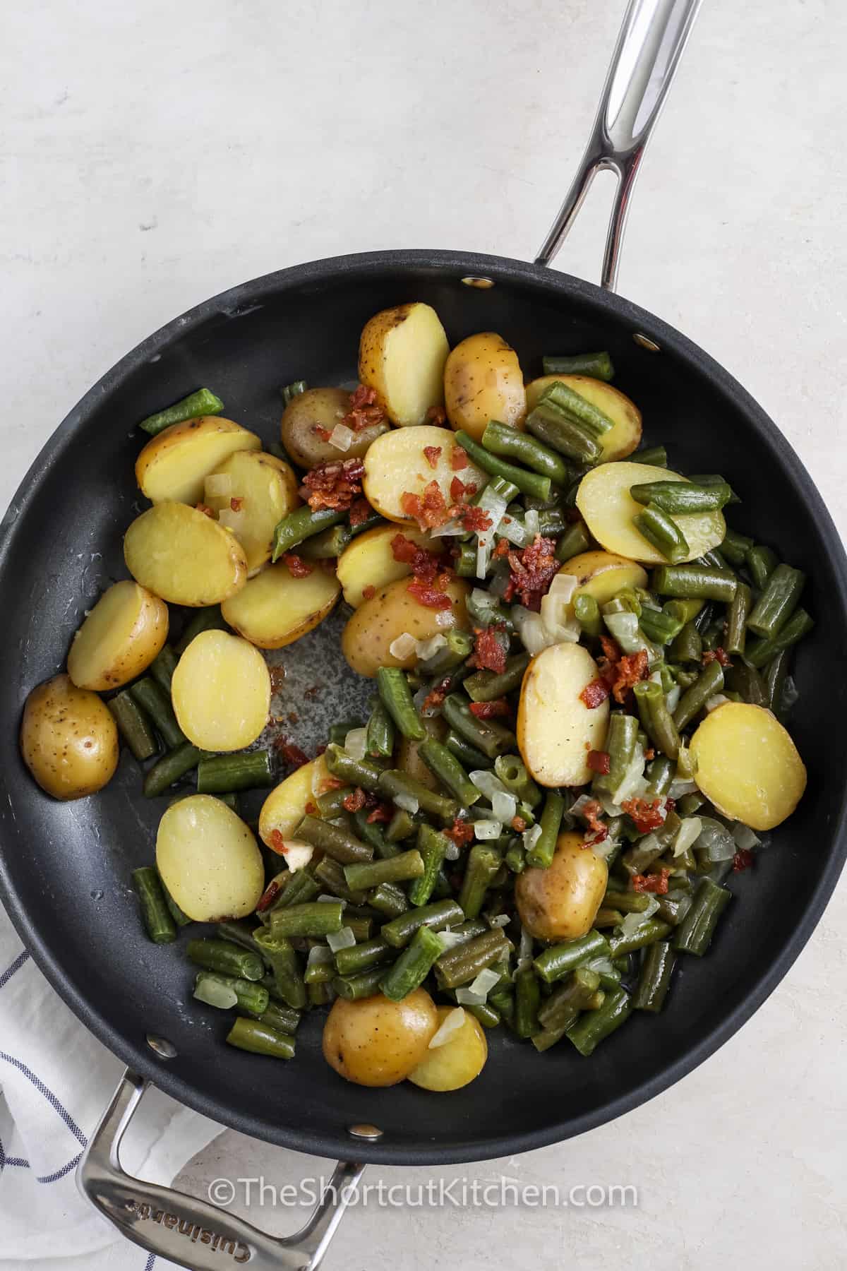 adding bacon to Green Beans and Potatoes in the pan