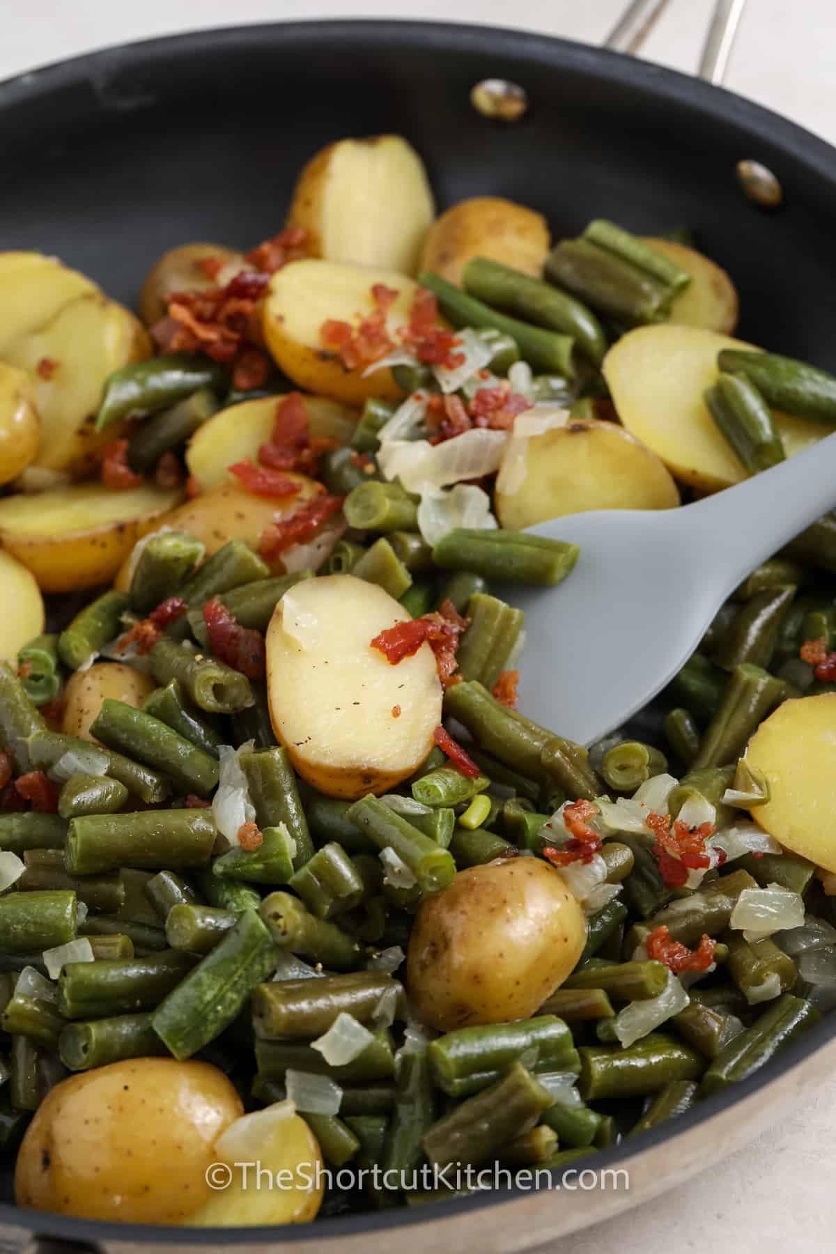 mixing ingredients together in pan to make Green Beans and Potatoes