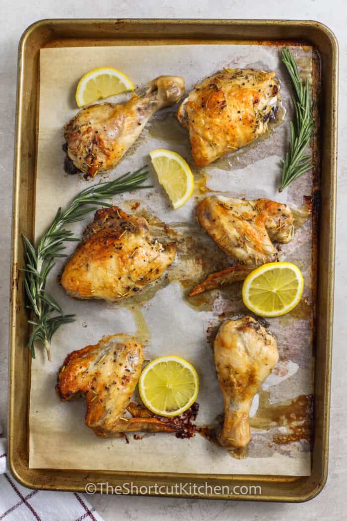 sheet pan of Lemon Rosemary Chicken pieces with lemon slices
