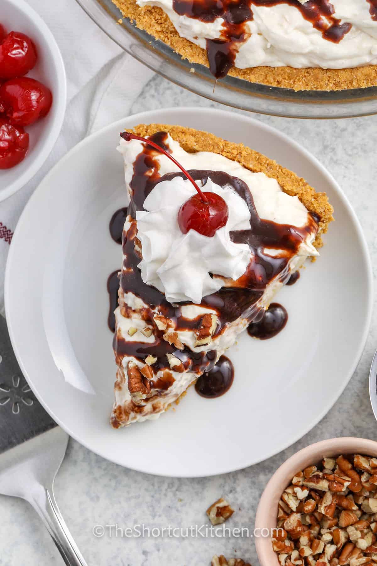 Banana Split Pie slice with chocolate syrup , whipped topping and cherry on top