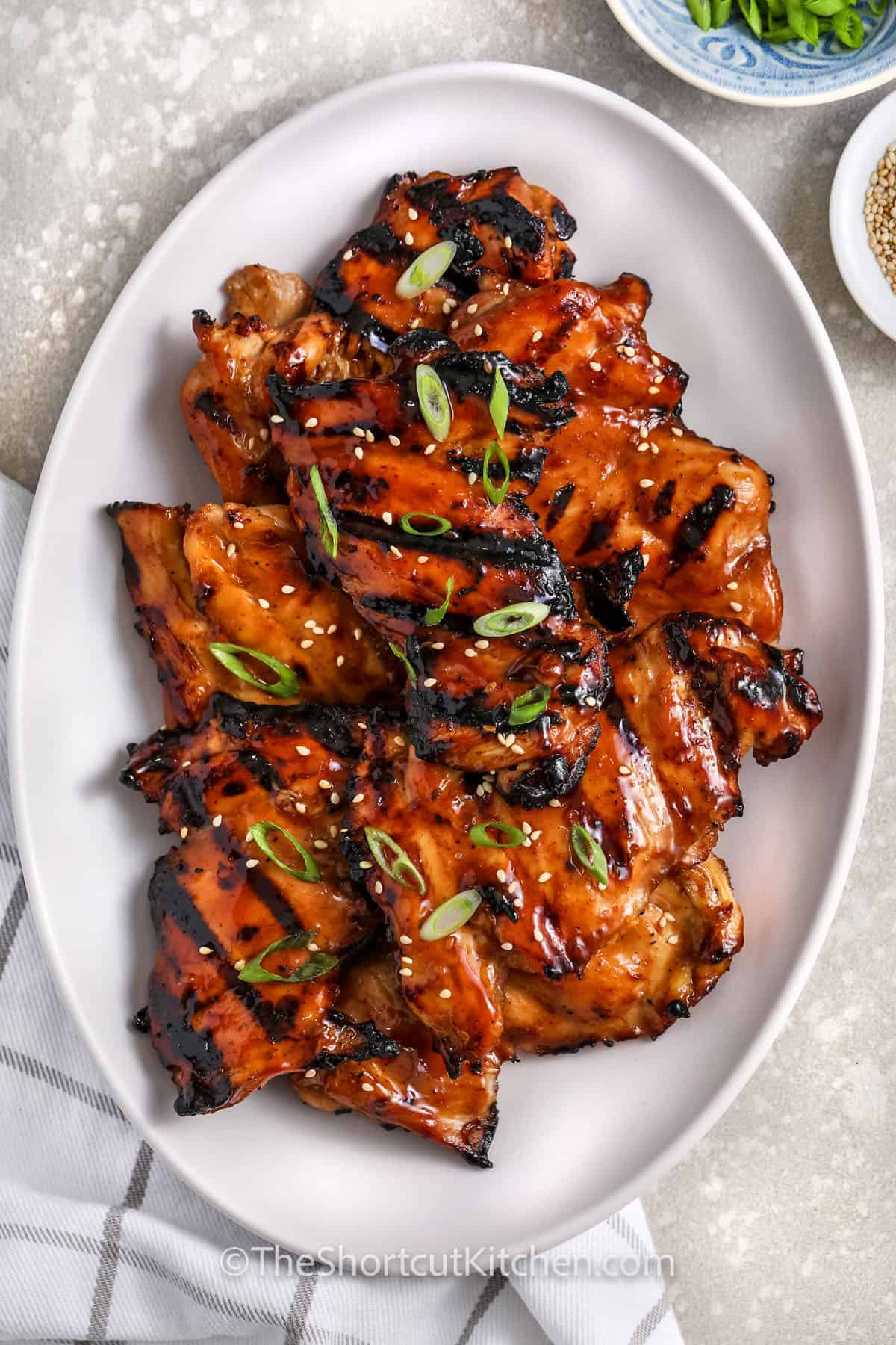 This easy grilled teriyaki chicken recipe keeps dinner simple with shortcut ingredients and big flavor. Chicken breasts or thighs are marinated in teriyaki sauce, grilled until juicy, and finished with a glossy brush of sauce before serving. Grilled teriyaki chicken is perfect with rice, salads, vegetables, or sliced cold for leftovers the next day. #theshortcutkitchen plated Grilled Teriyaki Chicken with green onions
