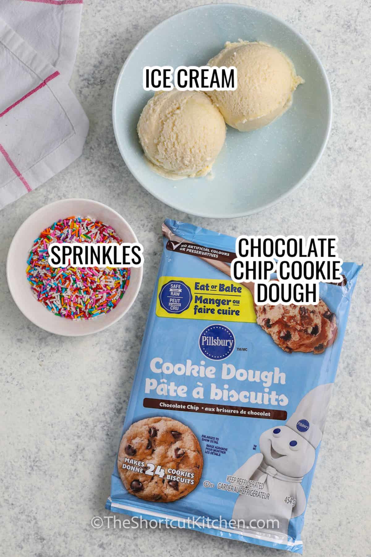 ingredients assembled to make ice cream cookie sandwiches, including ice cream, cookie dough, and sprinkles