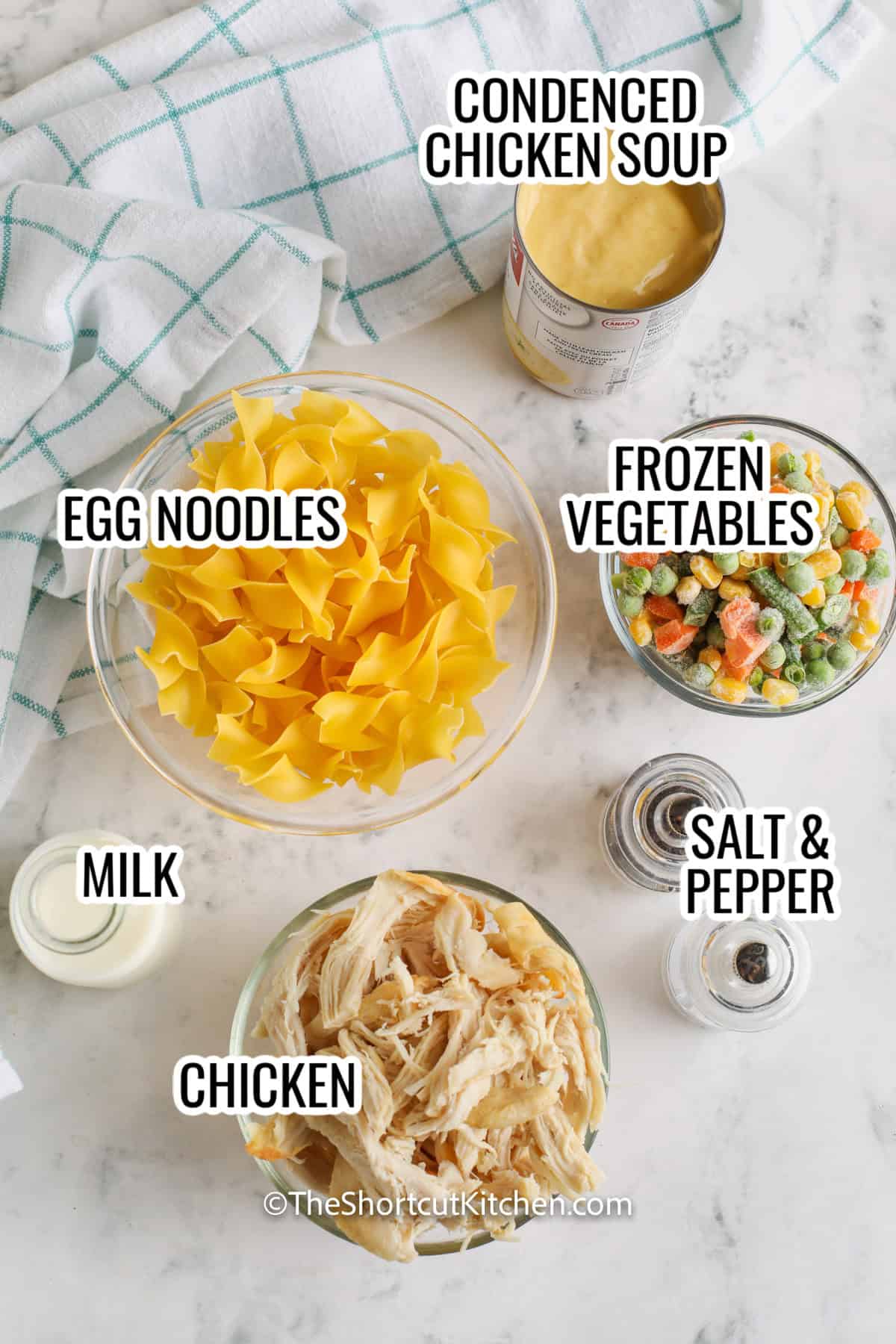 ingredients assembled to make chicken and egg noodles, including egg noodles, frozen vegetables, milk, condensed chicken soup, and chicken