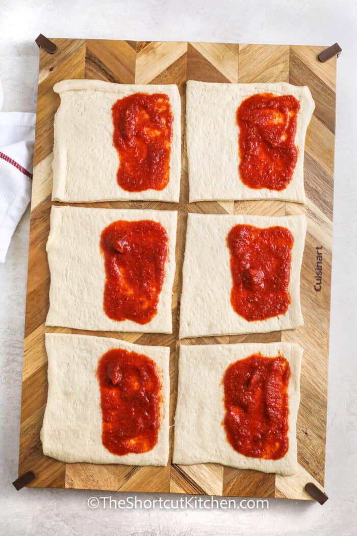 adding pizza sauce to biscuit dough to make Pizza Pockets