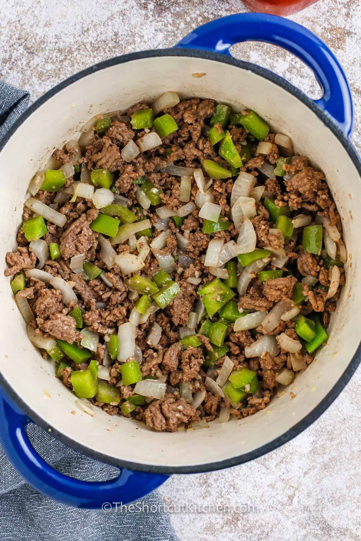 Save this hamburger macaroni soup for the next busy weeknight. It’s made with ground beef, onion, green pepper, garlic, and a rich tomato broth using condensed tomato soup, diced tomatoes, beef broth, and seasonings. Elbow pasta cooks in the soup for fewer dishes and cozy flavor. Serve with crackers or bread, and freeze extra portions for later. #theshortcutkitchen hamburger and hamburger macaroni soup in a pot