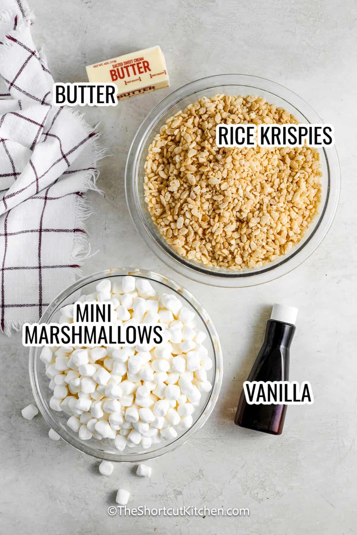 ingredients assembled to make rice krispies treats, including mini marshmallows, rice krispies cereal, butter, and vanilla,
