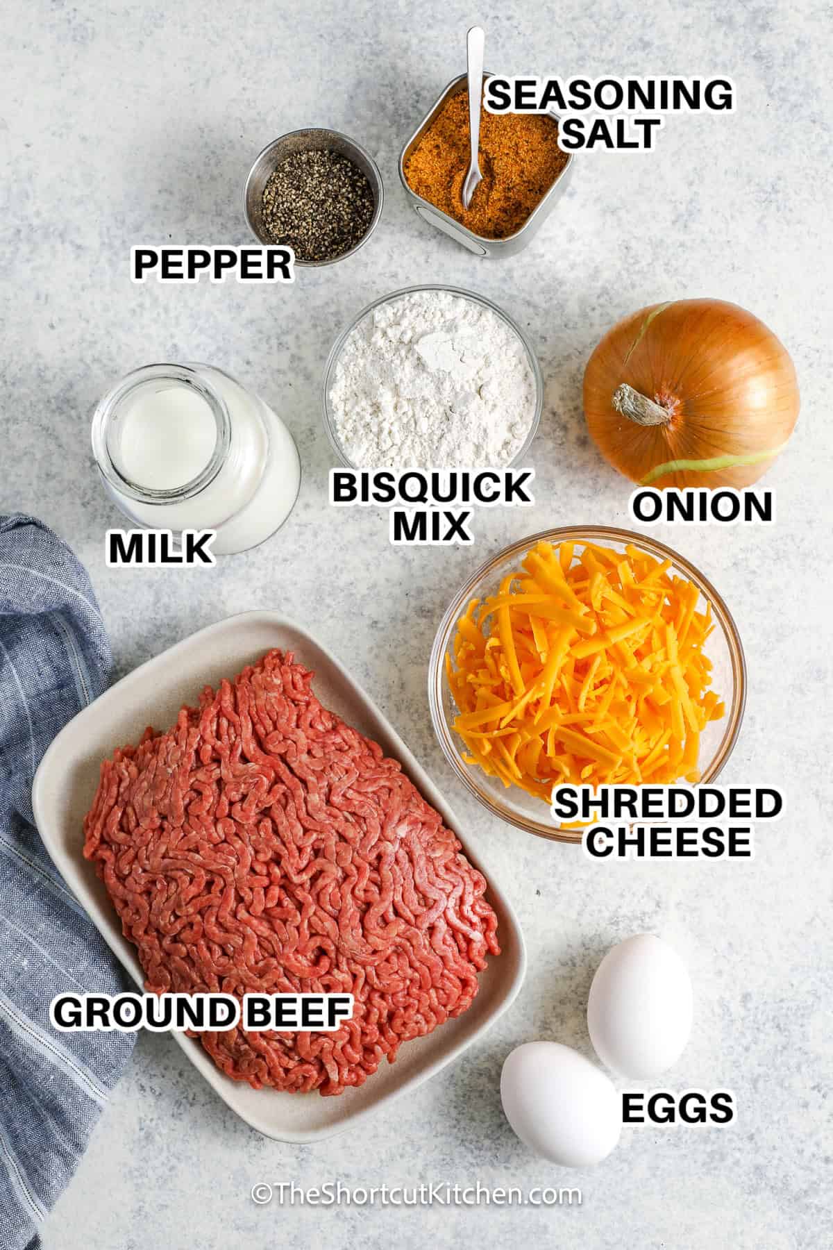 Ingredients to make bisquick cheeseburger pie labeled: seasoning salt, pepper, bisquick mix, onion, milk, shredded cheese, ground beef, eggs