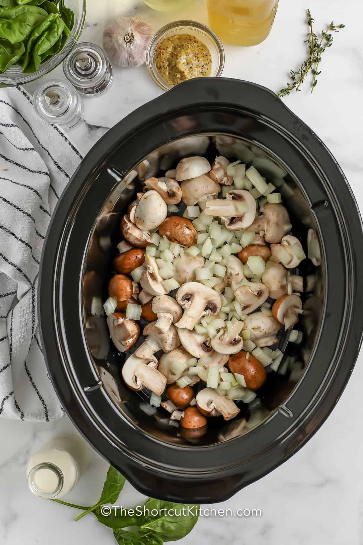 adding mushrooms and onions to pot to make Slow Cooker Chicken Thighs Recipe