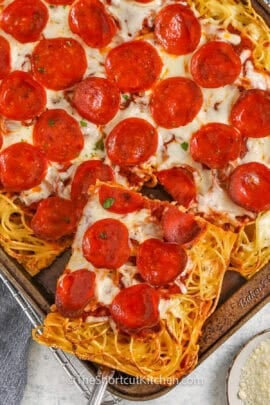 taking a slice of Spaghetti Pizza out of the sheet pan