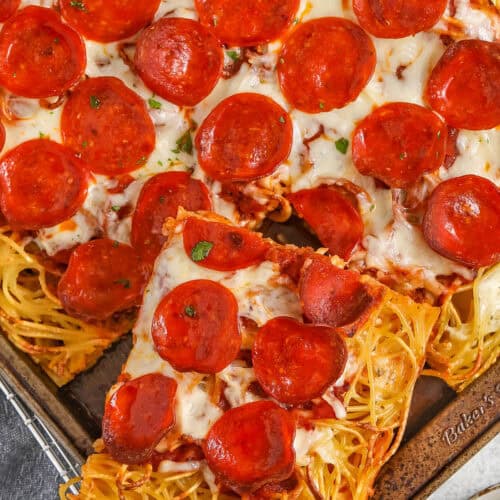 taking a slice of Spaghetti Pizza out of the sheet pan