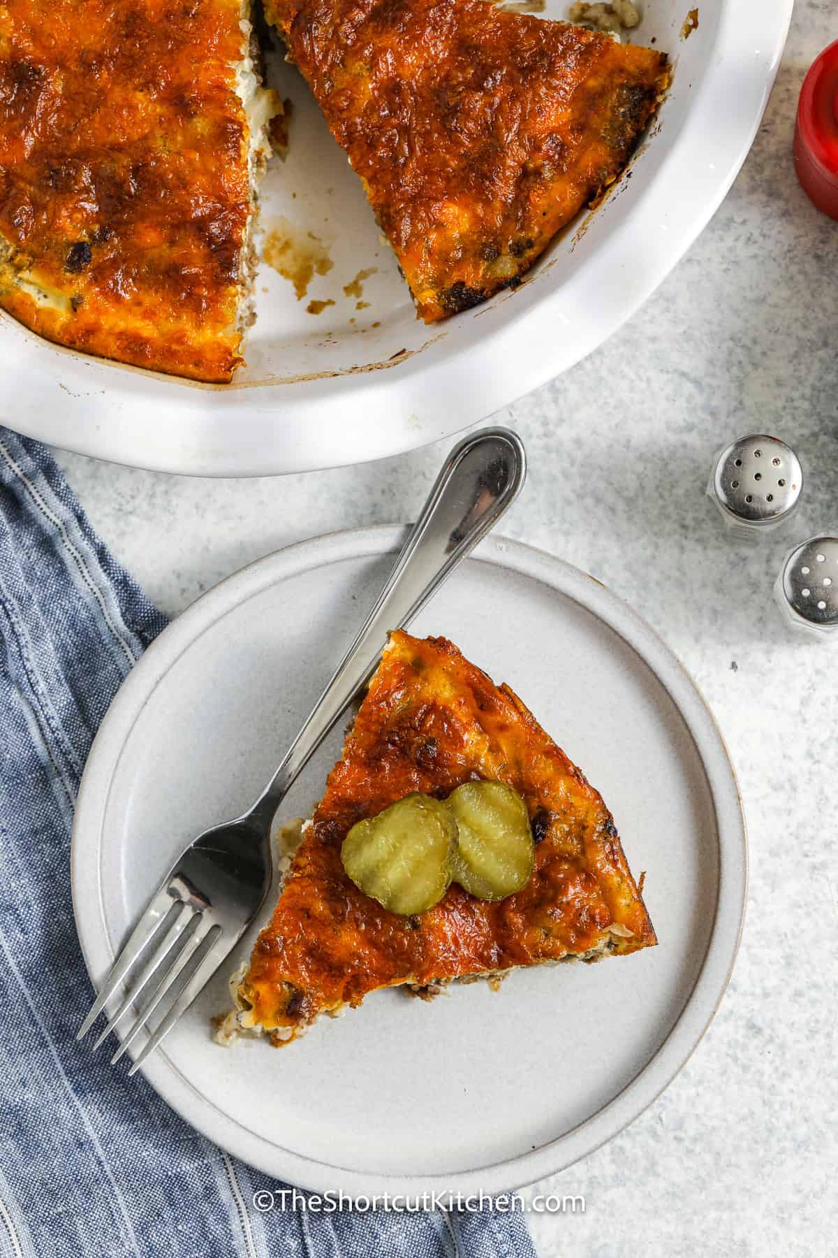 A slice of Bisquick Cheeseburger Pie on a plate topped with pickles