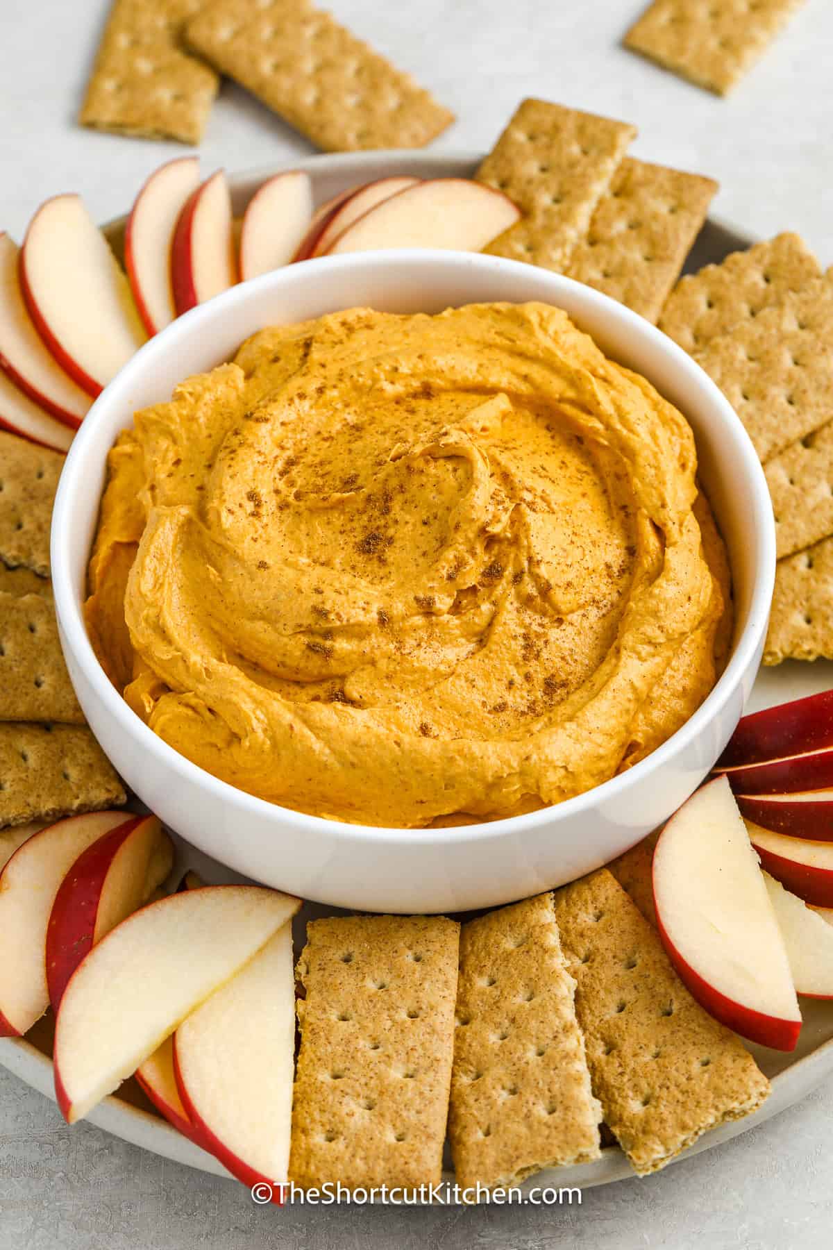 Pumpkin dip on a serving platter with apples and graham wafers