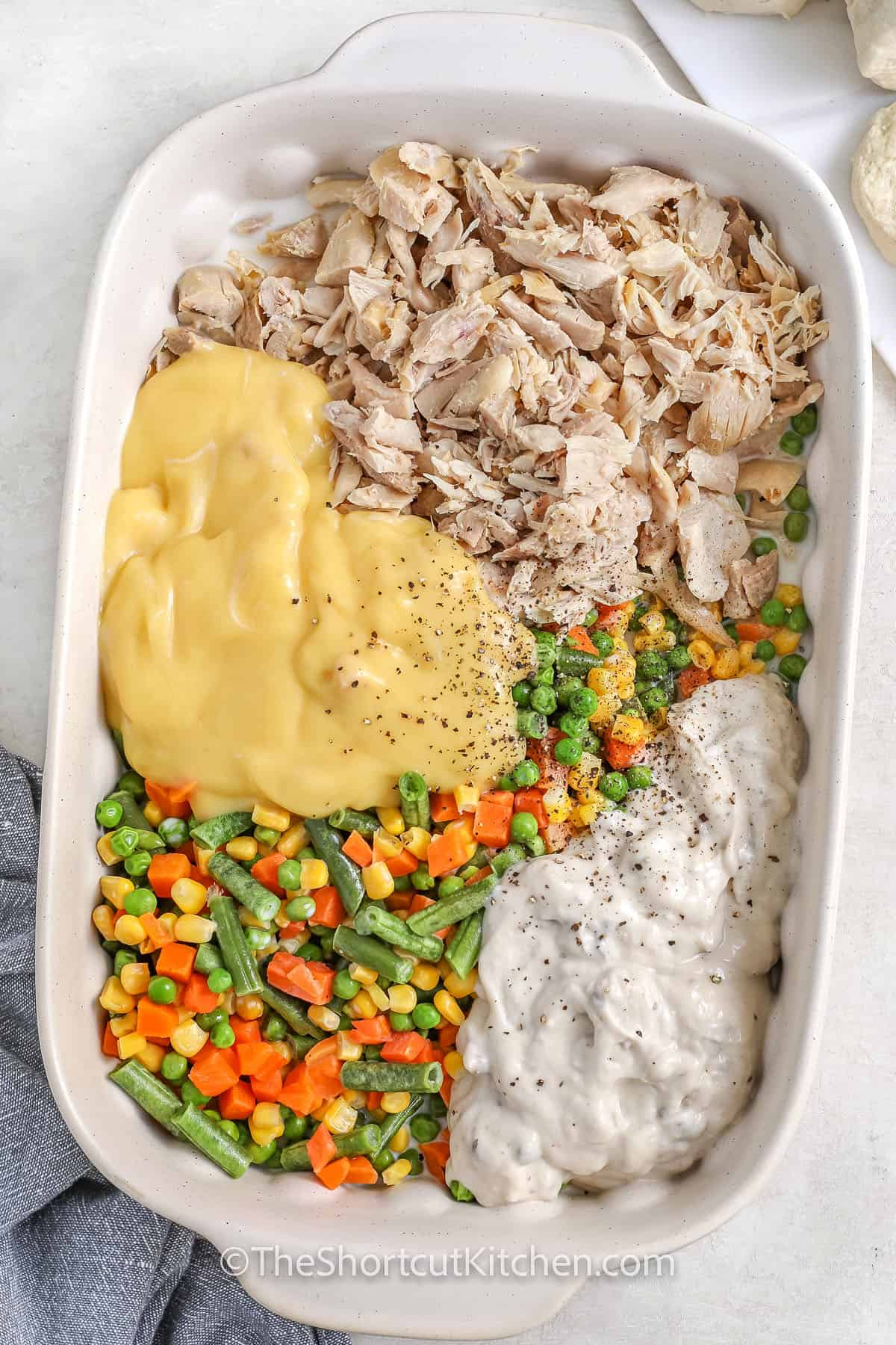 adding ingredients to casserole dish to make Easy Chicken Pot Pie Casserole