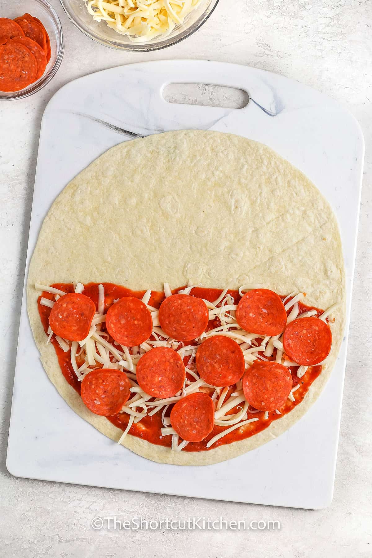 adding sauce , cheese and pepperoni to tortilla to make Pizza Quesadilla