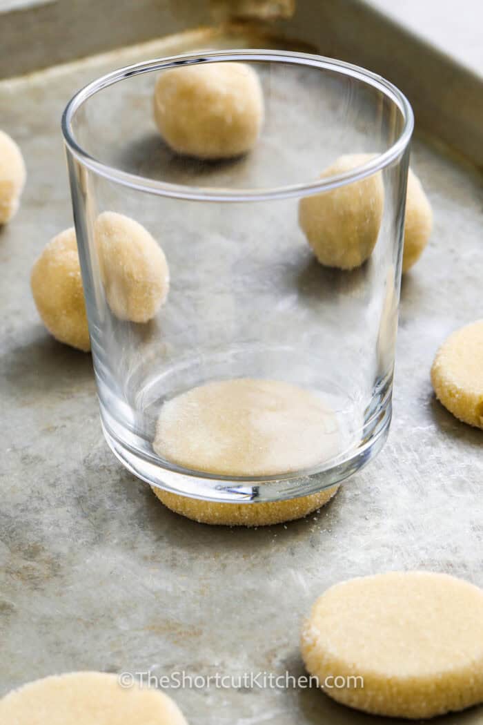 flattening cookie dough balls with a glass to make 3 Ingredient Sugar Cookie Recipe