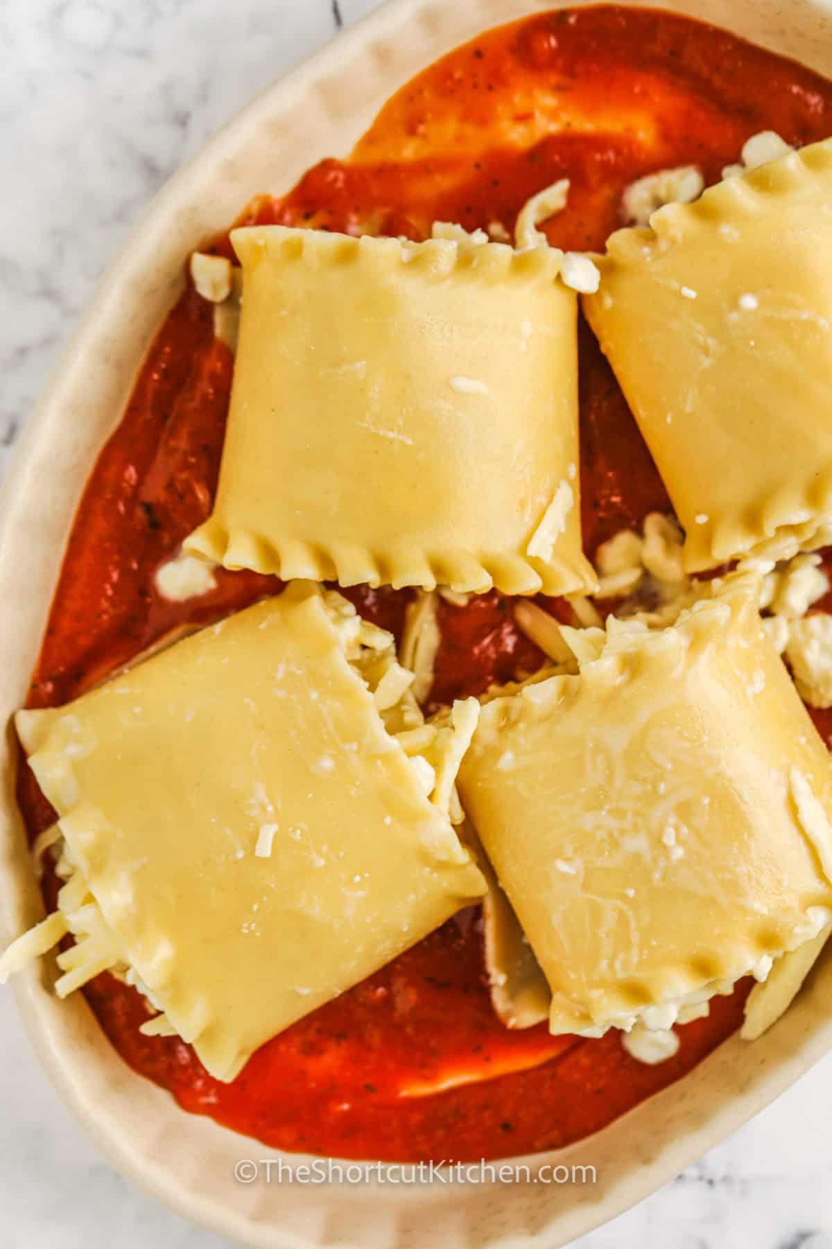 adding Three Cheese Lasagna Rolls to dish with sauce