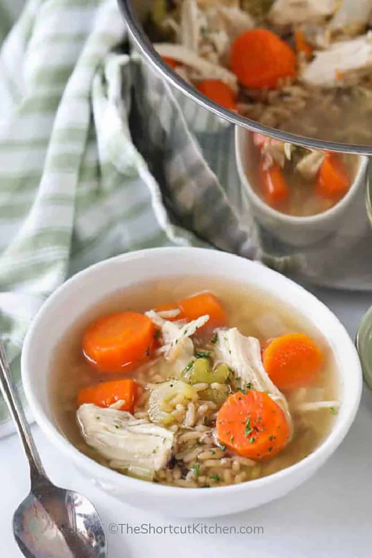 This chicken rice soup recipe is everything you need for a hearty, comforting meal. Fresh veggies, tender chicken, and instant rice come together in one pot for an easy, simple, and satisfying homemade dish. It’s perfect for lunch, dinner, or even meal prep. You’ll want to keep this one on hand for any occasion. #theshortcutkitchen Chicken Rice Soup Recipe in bowl and in a pot