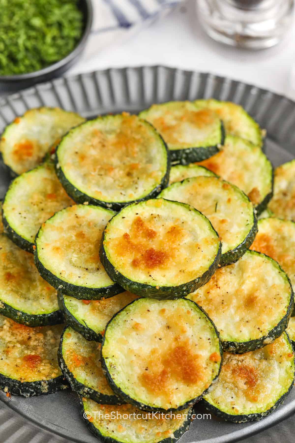 Crispy and delicious, baked parmesan zucchini is the ultimate side dish! These oven-baked bites are a flavorful addition to any meal, made with simple ingredients like zucchini slices, garlic, olive oil, and parmesan cheese. They’re quick to prepare, easy to bake, and a guaranteed hit for any occasion. Perfect as a snack or paired with your main dishes! #theshortcutkitchen cropped baked parmesan zucchini