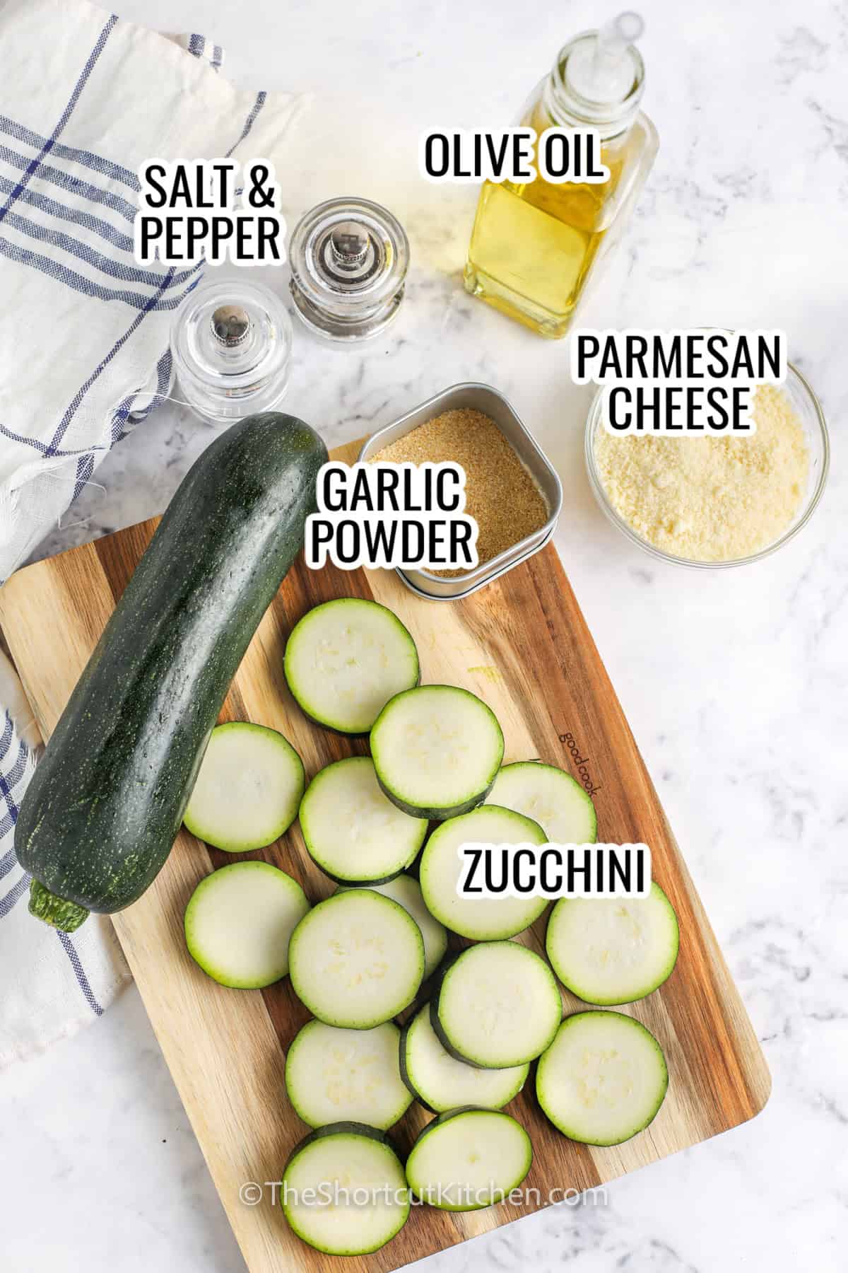 ingredients assembled to make baked parmesan zucchini, including zucchini, parmesan cheese, olive oil, garlic powder, and salt and pepper