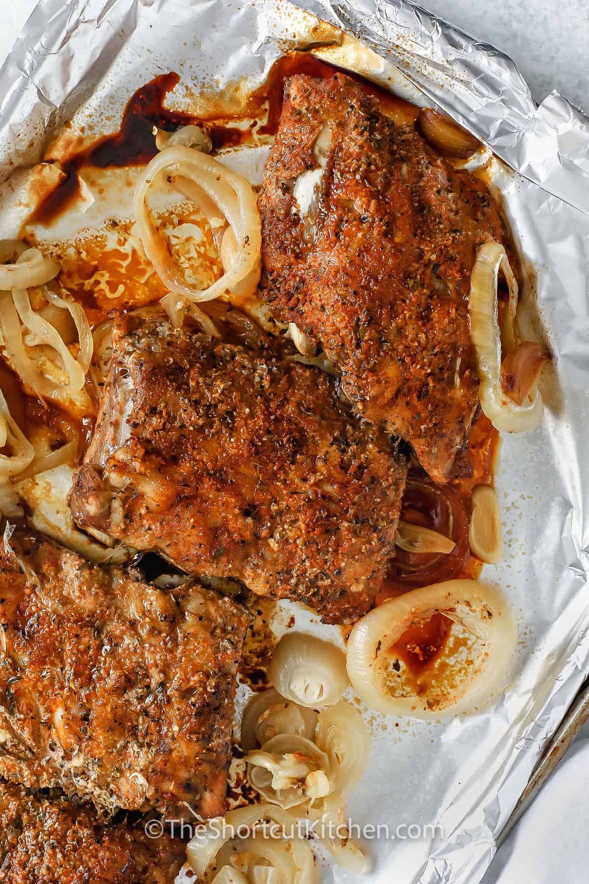 sheet pan of Oven Baked Ribs Recipe with onions