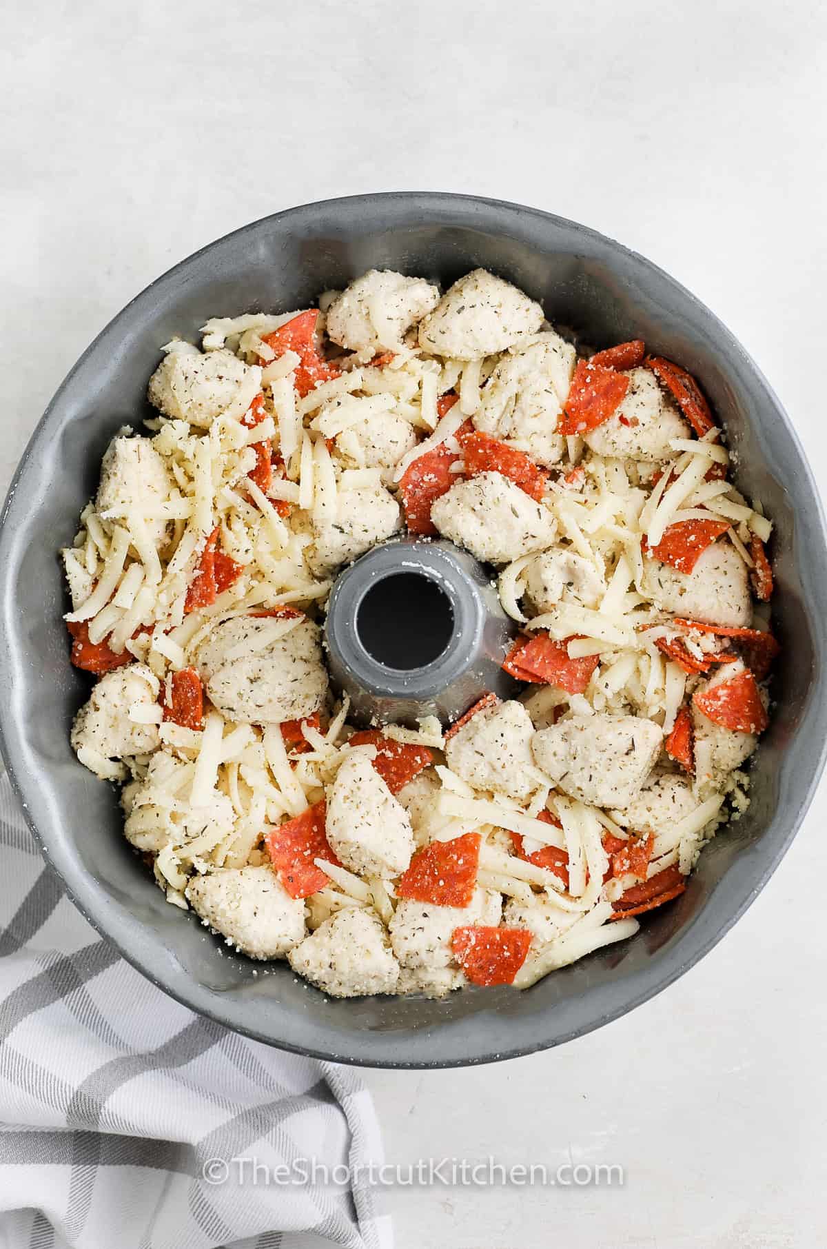adding ingredients to dish to make Pull Apart Pizza Bread