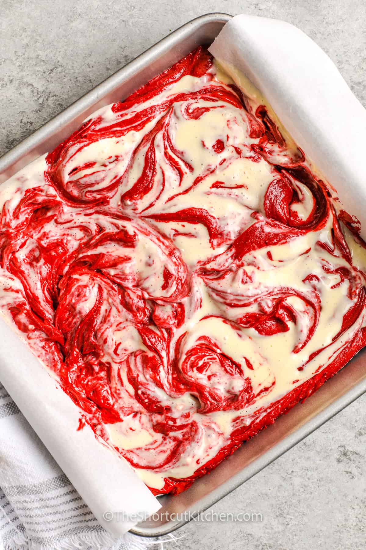 cream cheese mixture and red velvet brownie batter mixed in a dish