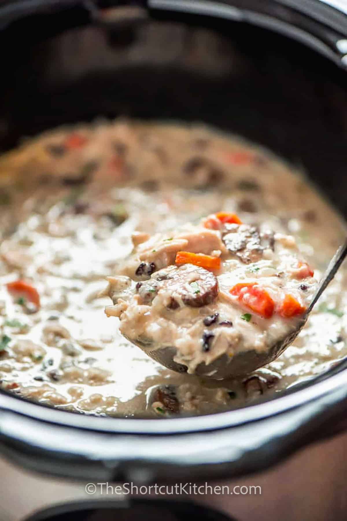 taking a spoonful of Slow Cooker Chicken Wild Rice Soup out of the pot