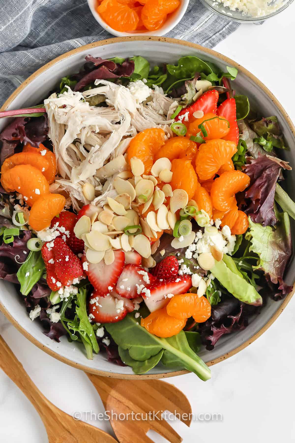This mandarin chicken salad recipe is a perfect blend of sweet and savory flavors with a delicious Asian twist. Juicy mandarin oranges, shredded chicken, and crunchy almonds are tossed with fresh greens and a sesame dressing. For extra texture, mix in pasta or crispy noodles, or try adding grapes for a burst of sweetness. Inspired by Chinese flavors, this light and refreshing dish is great for a quick meal. Enjoy a fresh, satisfying salad with balanced calories. #theshortcutkitchen ingredients in bowl to make Easy Mandarin Chicken Salad Recipe