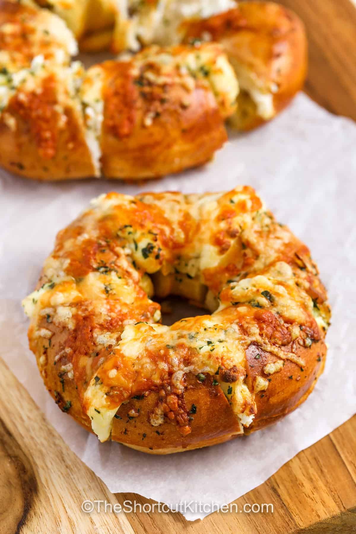 These stuffed bagels are an easy, cheesy air fryer recipe that’s packed with creamy, savory flavor. Sliced bagels get stuffed with cream cheese and gooey cheese, brushed with buttery garlic, then crisped to golden perfection. They make the best appetizer or snack for any occasion. Mix it up with different cheeses, seasonings, or even a bit of spice for a fun and flavorful twist! #theshortcutkitchen baked Stuffed Bagels on a wooden board