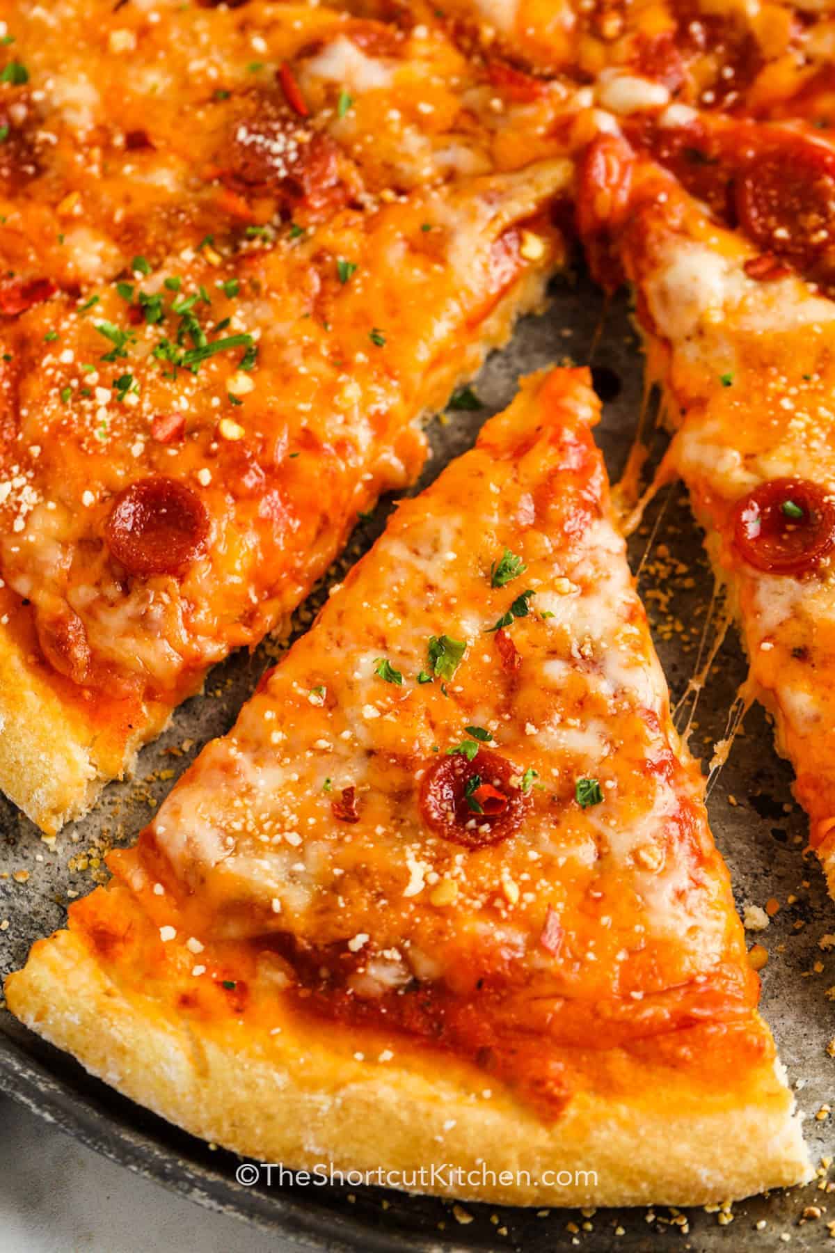 Homemade pizza tastes so great without preservatives so why not whip up a batch of this easy Bisquick pizza dough? It's super fast to make this recipe and it's mixed up without yeast for a quick rise time. Just use Bisquick for a tasty homemade crust, made thick or thin to individual preference. #theshortcutkitchen close up image of pizza for Bisquick Pizza Dough