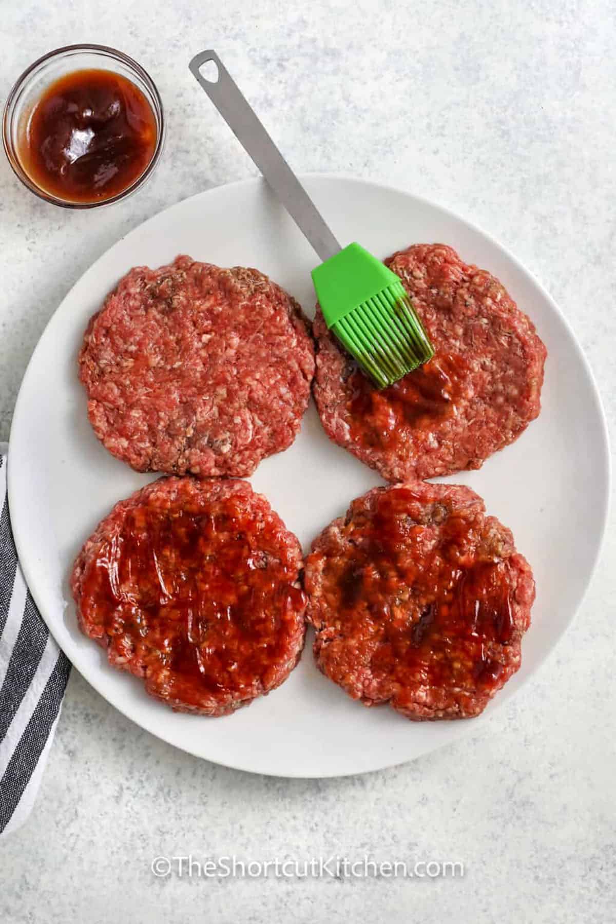 adding sauce to hamburger patties to make Great Grilled Burgers