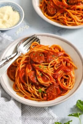 Italian Sausage Spaghetti in a bowl with a fork and spoon