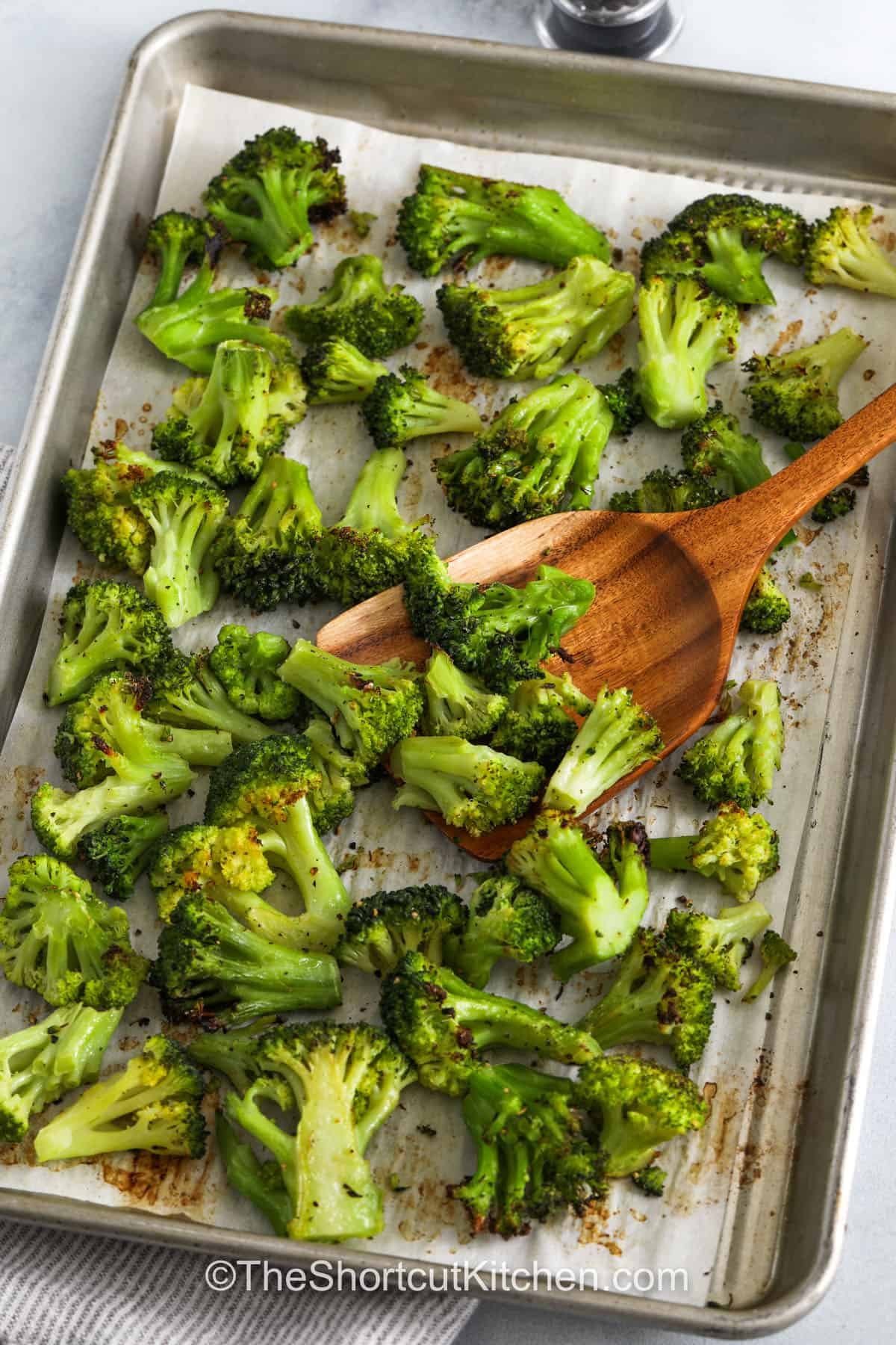 Roasted Frozen Broccoli on a sheet pan with a wooden spoon