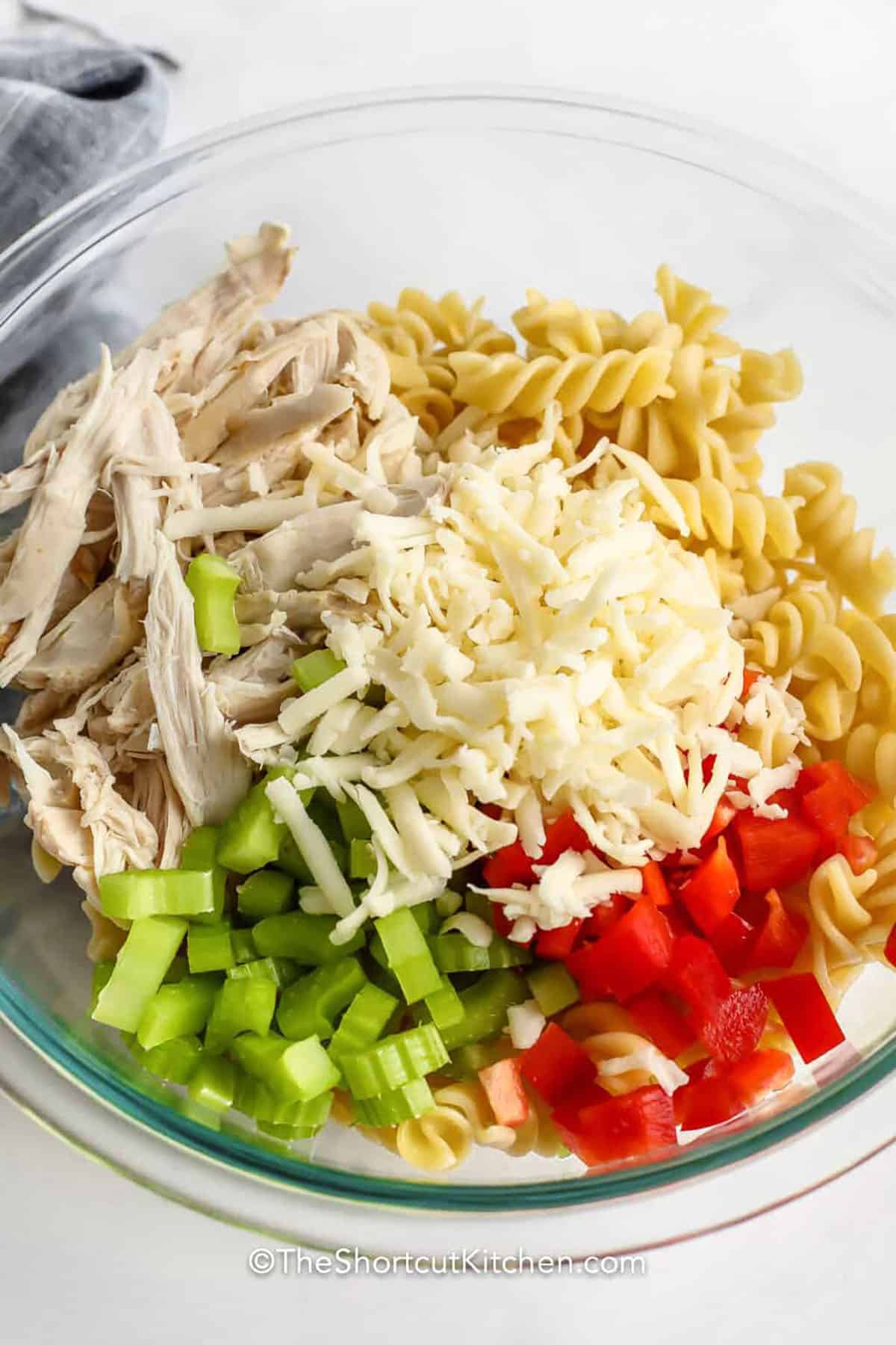 adding ingredients to bowl to make Buffalo Chicken and Pasta Salad