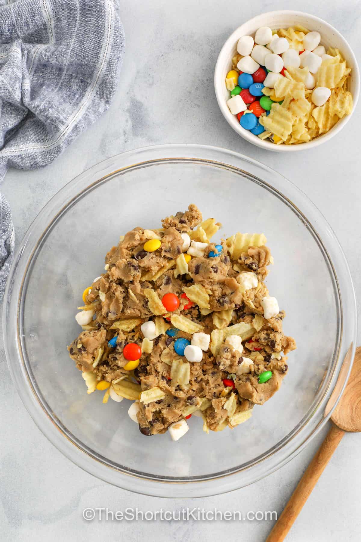 mixing toppings with cookie dough to make Kitchen Sink Cookies