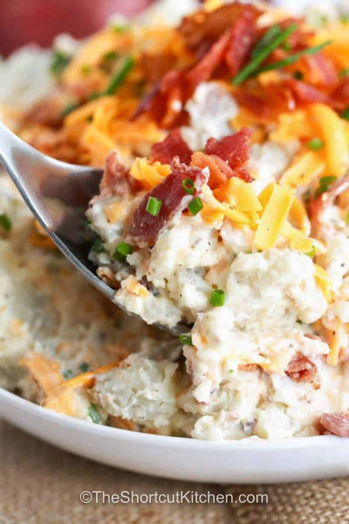 taking a spoonfull of Loaded Potato Salad Recipe out of the bowl