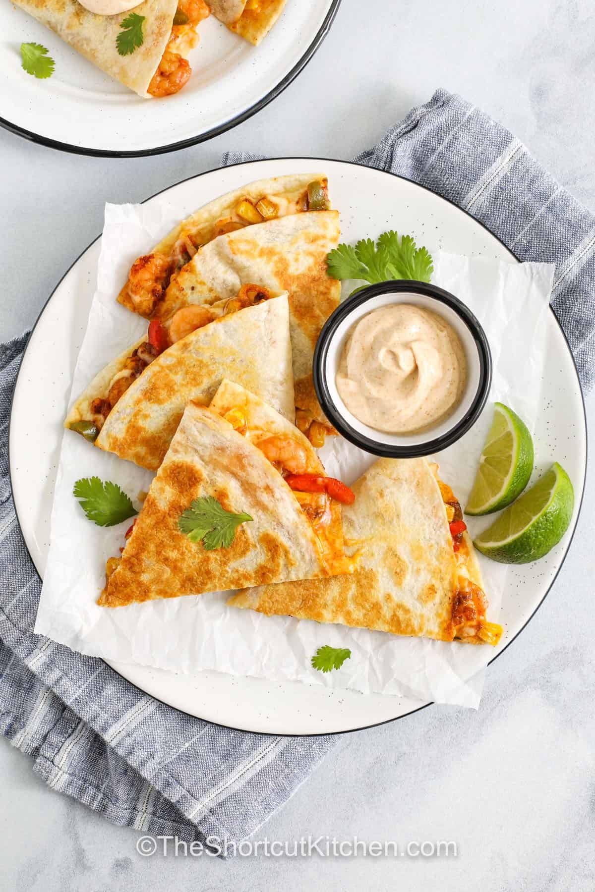 Shrimp quesadillas are the perfect weeknight dinner—fast, flavorful, and packed with cheesy goodness. Using frozen shrimp and veggies saves time while still delivering big taste. Just heat, fill, and cook until crisp for a crowd-pleasing meal that’s ready in under 20 minutes. They’re great for using pantry staples and freezer finds. #theshortcutkitchen plated Shrimp Quesadillas with lime