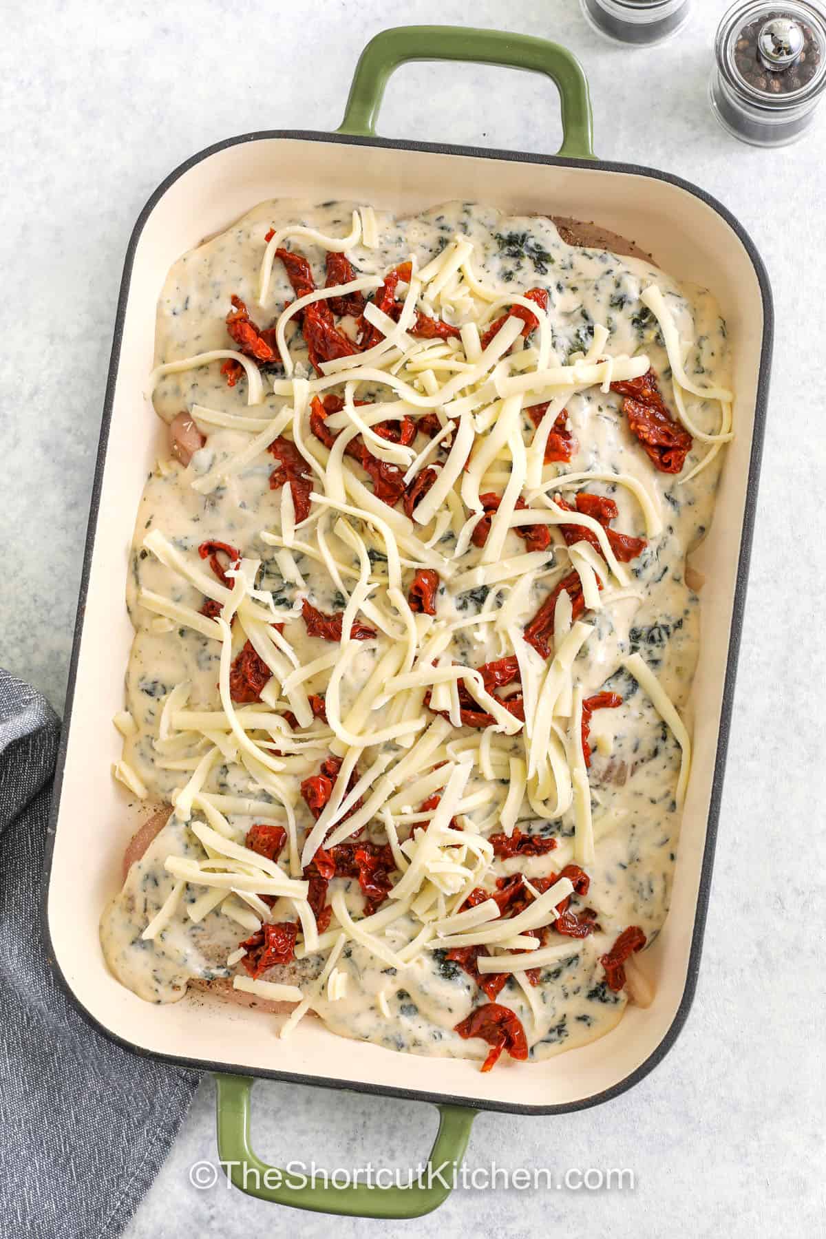 adding cheese and sundried tomatoes to dish to make Baked Tuscan Chicken